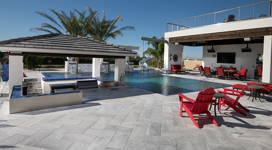 Expansive marble paving and sunken kitchen around modern designed pool with 2nd story sun deck